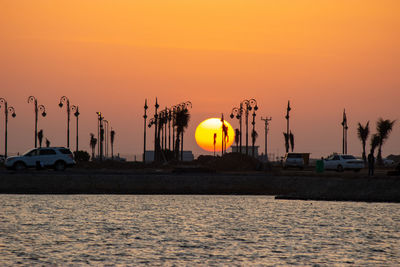 Silhouette sailboats in sea against orange sky