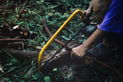 Midsection of man cutting wood