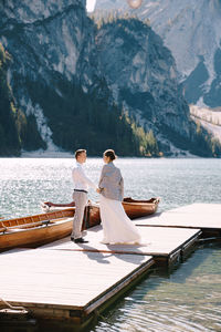 Rear view of people sitting on lake against mountain