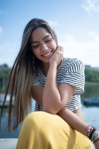 Portrait of smiling young woman sitting at beach