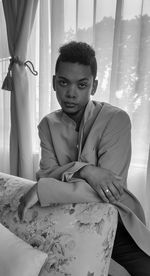 Portrait of young man sitting on bed at home