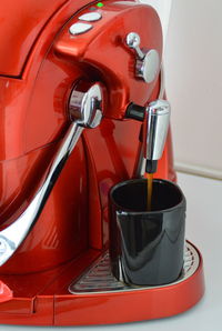 Close-up of machine pouring coffee in cup at cafe