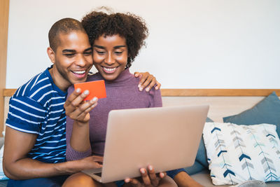 Smiling couple making payment for online shopping over laptop