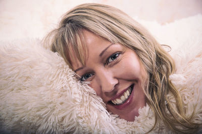 Close-up portrait of smiling mature woman relaxing on fur bed at home