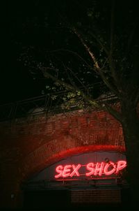 Low angle view of illuminated text on tree at night