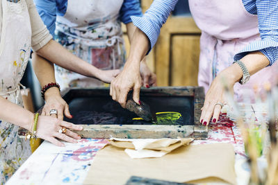 Faceless women in art studio working with silkscreen creating fabric print