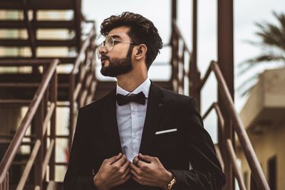 Businessman looking away while wearing suit by railing