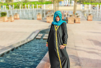 Portrait of woman standing by artificial pond