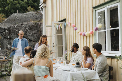 Smiling woman serving food to male and female friends during dinner party at cafe