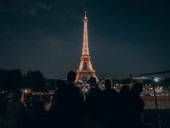 People at illuminated city against sky