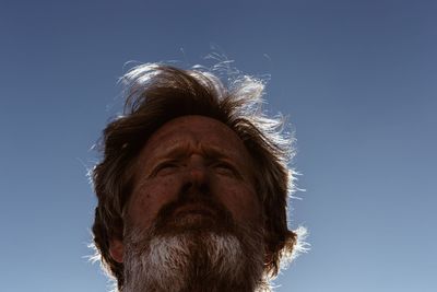 Low angle portrait of man against blue sky