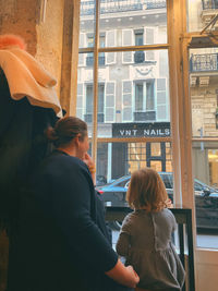 Rear view of woman standing by window