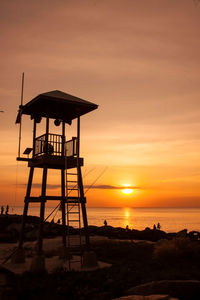 Lifeguard hut at beach against sky during sunset