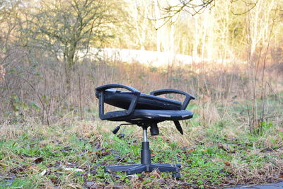 Close-up of empty bench on field against sky