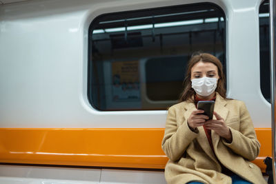 Woman using phone while sitting in train