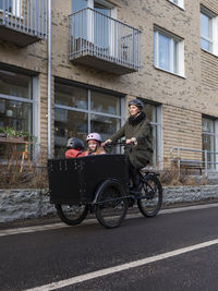 Young mother cycling with two children in cargo bicycle