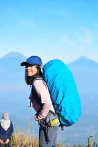 Friends standing on mountain against blue sky