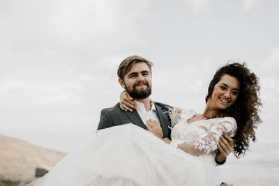 Portrait of smiling young couple against sky