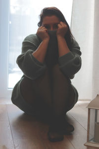 Low section of woman sitting on floor at home