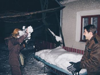 Siblings playing with snow at night