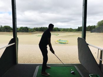 Full length of man playing soccer against sky