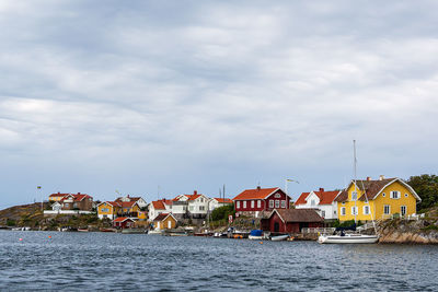 Houses by river against buildings in city against sky