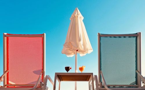 Low angle view of chair on table against clear blue sky