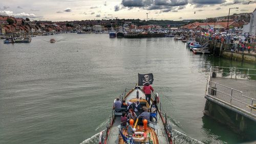 People on boat sailing in river against sky