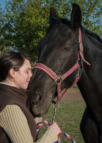 Smiling woman standing with horse on grassy field at farm