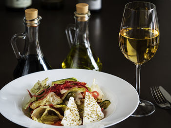 High angle view of greek salad with white wine on table