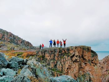 Rear view of people standing on rock against sky