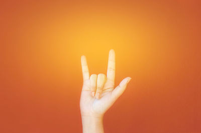 Close-up of hand against orange background