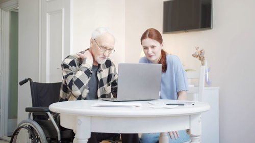 Nurse teaching laptop to senior patient