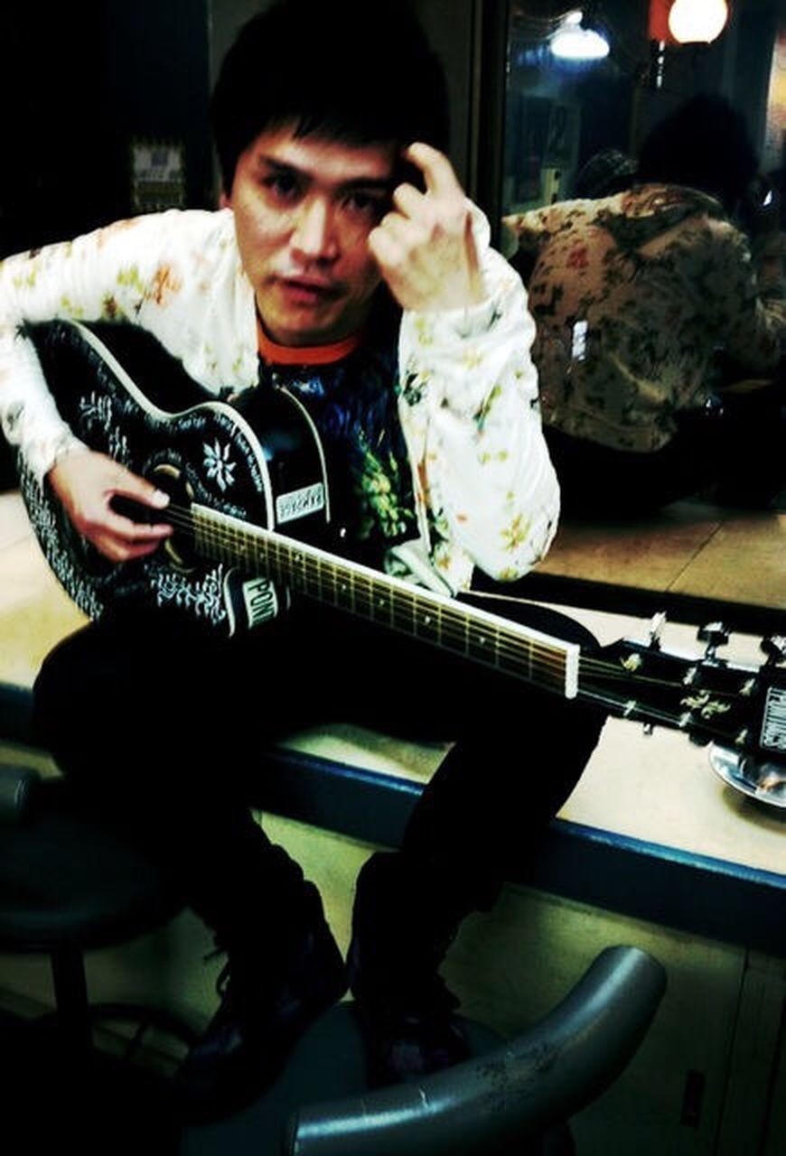 indoors, one person, adult, young adult, music, young men, men, communication, technology, holding, arts culture and entertainment, males, playing, musical instrument, guitar, artist, sitting, clothing, business, electric guitar