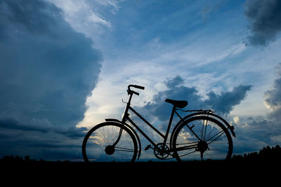 Low angle view of silhouette bicycle on field against sky