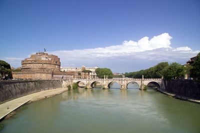 Arch bridge over river against blue sky