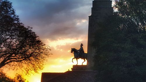 Silhouette statue against sky during sunset