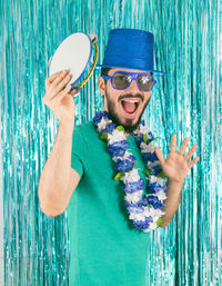 Portrait of happy man holding pandeiro against wall