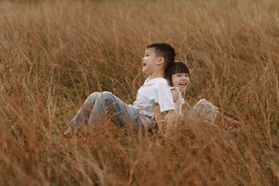 Smiling siblings sitting on grassy field