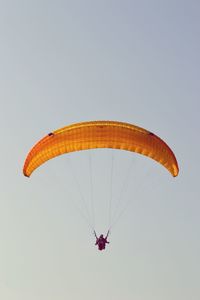 Low angle view of man paragliding against clear sky