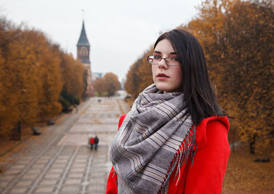 Portrait of young woman standing against trees during winter