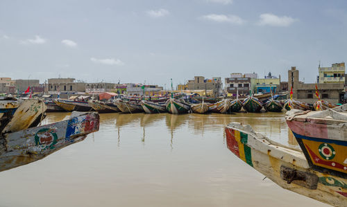 Boats moored in city against sky