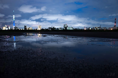 View of illuminated cityscape against cloudy sky