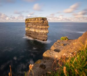 Rock formation on sea shore against sky