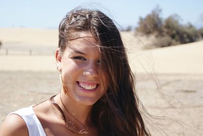 Portrait of happy young woman at sandy beach