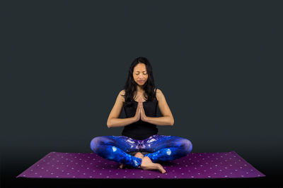 Young woman sitting against black background