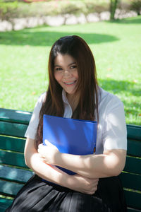 Portrait of young woman holding blue file