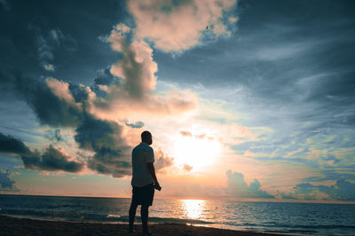 Man standing on beach at sunset or sunrise