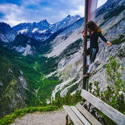 Full length of woman standing on pole against mountain range