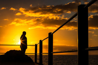 Silhouette man standing by sea against sky during sunset